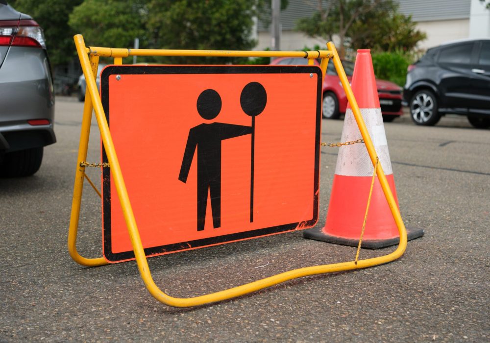 An orange metal traffic controller ahead sign